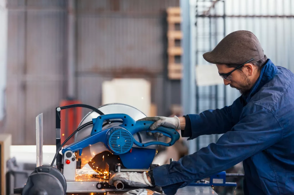 Side view of bearded master working with saw machine